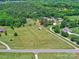 Lush aerial view showcasing a well-maintained field with residences, storage building and surrounding mature trees, giving a spacious feel at 11850 Sugar Hill Rd, Davidson, NC 28036