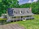 Inviting two-story home featuring a spacious wraparound porch, providing a perfect spot for relaxing and enjoying the outdoors at 11850 Sugar Hill Rd, Davidson, NC 28036