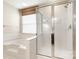 Bathroom featuring white tile tub-shower combo with glass door and window with blinds at 12824 Harvest Time Ct, Charlotte, NC 28278
