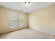 Bedroom with neutral carpeting, two windows with blinds, and soft yellow walls at 12824 Harvest Time Ct, Charlotte, NC 28278