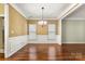 Dining room boasts hardwood floors, a chandelier, wainscoting, and natural light through the windows at 12824 Harvest Time Ct, Charlotte, NC 28278