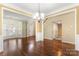 Open-concept living room featuring hardwood floors, staircase, natural light, and stylish chandelier at 12824 Harvest Time Ct, Charlotte, NC 28278