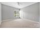 A spacious bedroom with neutral carpet, a window overlooking the grounds, and a ceiling fan at 17111 Doe Valley Ct, Cornelius, NC 28031