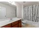Well-lit bathroom boasting a modern vanity, toilet, and shower/tub combo with sleek patterned curtain at 18460 W Catawba Ave, Cornelius, NC 28031