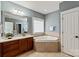 Elegant bathroom with a corner tub, wood vanity, and ample natural light through a glass block window at 189 Mills Ln, Fort Mill, SC 29708