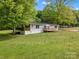 Back of house featuring a wood deck, green lawn and tree lined perimeter at 195 Bluebird Ln, Salisbury, NC 28146