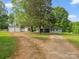Charming single-story home with large trees, gravel driveway, detached garage, and outbuildings at 195 Bluebird Ln, Salisbury, NC 28146