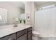 Bathroom featuring gray cabinets, quartz countertop, shower with white curtain, and tiled walls at 20396 Queens St, Cornelius, NC 28031