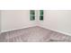A simple, carpeted bedroom provides plenty of natural light through two windows at 20396 Queens St, Cornelius, NC 28031