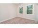 A simple, carpeted bedroom provides plenty of natural light through two windows at 20396 Queens St, Cornelius, NC 28031