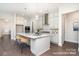 Bright kitchen features a spacious island with seating, stainless steel appliances and gray cabinets and hardwood flooring at 20396 Queens St, Cornelius, NC 28031