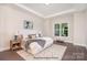 Serene main bedroom featuring hardwood floors, a tray ceiling, a large window, and neutral decor at 20396 Queens St, Cornelius, NC 28031