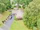 Aerial view of a brick home with a spacious yard, a long driveway, and mature trees surrounding the property at 211 General Stonewall Jackson Dr, Stanley, NC 28164