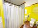 Unique bathroom with bright yellow walls, vinyl flooring, toilet, vanity, and shower with curtain at 211 Spruce St, Badin, NC 28009