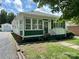 Charming home featuring green and white exterior paint, well-maintained lawn, and a detached one-car garage at 211 Spruce St, Badin, NC 28009