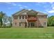 Expansive brick home featuring a covered patio and a large yard with lush, green grass at 2185 Loire Valley Dr, Fort Mill, SC 29707