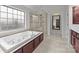 Bright bathroom features a large soaking tub, glass shower, neutral tile, and natural light from a large window at 3206 Lakehurst Xing, Matthews, NC 28104