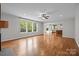 Open living room featuring hardwood floors, a ceiling fan, and large windows overlooking the front yard at 3206 Lakehurst Xing, Matthews, NC 28104