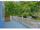 A view of the spacious blue painted back deck with white railing and view of the wooded backyard at 331 Solomon St, Charlotte, NC 28216