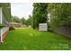 Green backyard featuring an outbuilding and fenced in property line surrounded by mature trees at 405 N Woodland Dr, Lancaster, SC 29720