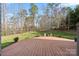 A wooden deck overlooks a lush backyard with a fire pit area and mature trees at 4095 Harmattan Dr, Denver, NC 28037