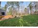 A lush green backyard features a wooden deck, a fire pit, and mature trees at 4095 Harmattan Dr, Denver, NC 28037