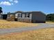Charming gray home featuring a gravel driveway, wooden steps, and brick foundation at 493 Eagle Mills Rd, Hamptonville, NC 27020
