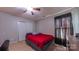Bedroom features neutral carpet, ceiling fan, closet doors, and a red comforter at 5003 Singletree Ln, Indian Trail, NC 28079