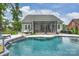 Backyard view of a freeform pool, screened-in porch, outdoor kitchen, and patio area at 562 Preservation Dr, Fort Mill, SC 29715