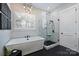 This bathroom has a soaking tub next to the window and a glass shower with black and white marble-style tile at 562 Preservation Dr, Fort Mill, SC 29715
