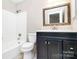 Bathroom features a dark vanity with a white countertop and a tub with white tile surround at 7123 Meeting St, Charlotte, NC 28210