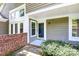 Inviting entryway with brick accents, a storm door, and lush landscaping creating a welcoming first impression at 7123 Meeting St, Charlotte, NC 28210