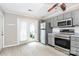 Bright kitchen featuring stainless steel appliances, gray cabinets, and a door leading to the outdoor area at 7123 Meeting St, Charlotte, NC 28210