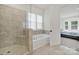 Well-lit bathroom showcasing a glass enclosed shower and a separate soaking tub by a window at 7160 Sumters Camp Trl, Indian Land, SC 29707