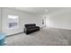 Spacious bonus room with neutral carpet, large windows, and a comfortable black leather sofa at 7160 Sumters Camp Trl, Indian Land, SC 29707