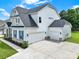 Stunning two-story home featuring white siding, stone accents, three-car garage, and lush green landscaping at 7160 Sumters Camp Trl, Indian Land, SC 29707