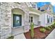 Close-up of a stone arched entrance with teal front door, mulch landscaping, and exterior columns at 7160 Sumters Camp Trl, Indian Land, SC 29707