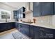 Modern kitchen features navy cabinets, white countertops, stainless steel vent hood, and mosaic tile backsplash at 7160 Sumters Camp Trl, Indian Land, SC 29707