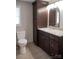 This bathroom features a toilet, dark cabinets, granite countertop and neutral tile flooring at 728 Morningside Dr, Mount Holly, NC 28120