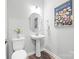 Bright powder room featuring pedestal sink, unique mirror, and wood-look floors at 9109 Liberty Hill Dr, Mint Hill, NC 28227