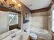 Well-lit bathroom with a window, built-in cabinet, tile accents, and a shower-tub combo at 1000 Sarandon Dr, Matthews, NC 28104