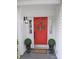Close-up of a vibrant red front door with a decorative wreath, flanked by potted topiaries on a covered porch at 1051 Streamlet Way, Monroe, NC 28110