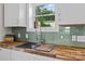 Well-lit kitchen with butcher block counters, undermount sink, and modern green tile backsplash at 134 Snowbird Loop, Statesville, NC 28625