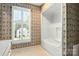 Bright bathroom featuring wallpaper, white-framed window, and white tub with a shower at 147 35Th Ne Ave, Hickory, NC 28601