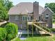 Rear view of a brick home with a deck, stairs, and well-manicured lawn, creating a welcoming outdoor space at 1508 Avalon Oaks Ct, Dallas, NC 28034