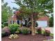 Beautiful brick home with meticulously landscaped front yard featuring vibrant flowers and mature trees at 15826 Hollingbourne Rd, Huntersville, NC 28078