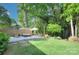 Serene backyard featuring a patio, lounge seating, lush lawn, privacy fence, and mature trees at 1715 Wensley Dr, Charlotte, NC 28210