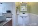 Classic half bath featuring a pedestal sink, wainscoting, and decorative mirror with easy access to the bedroom at 1715 Wensley Dr, Charlotte, NC 28210