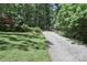 Long gravel driveway with greenery and trees leading to outbuilding at 173 Rocky River Rd, Mooresville, NC 28115