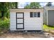 Detached shed featuring white siding, a black door, and a window at 1746 2Nd Street Sw Pl, Hickory, NC 28602